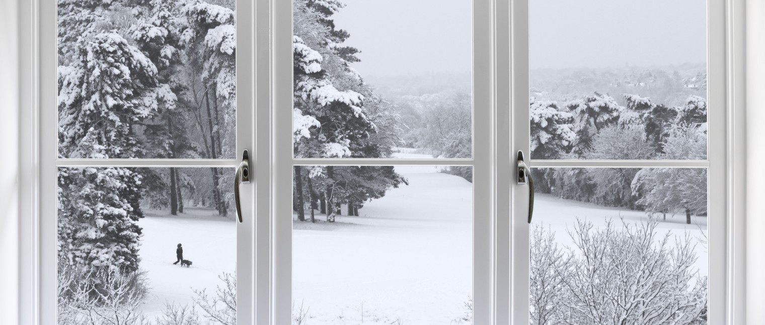 A winter view out of a large bay window in a living room.