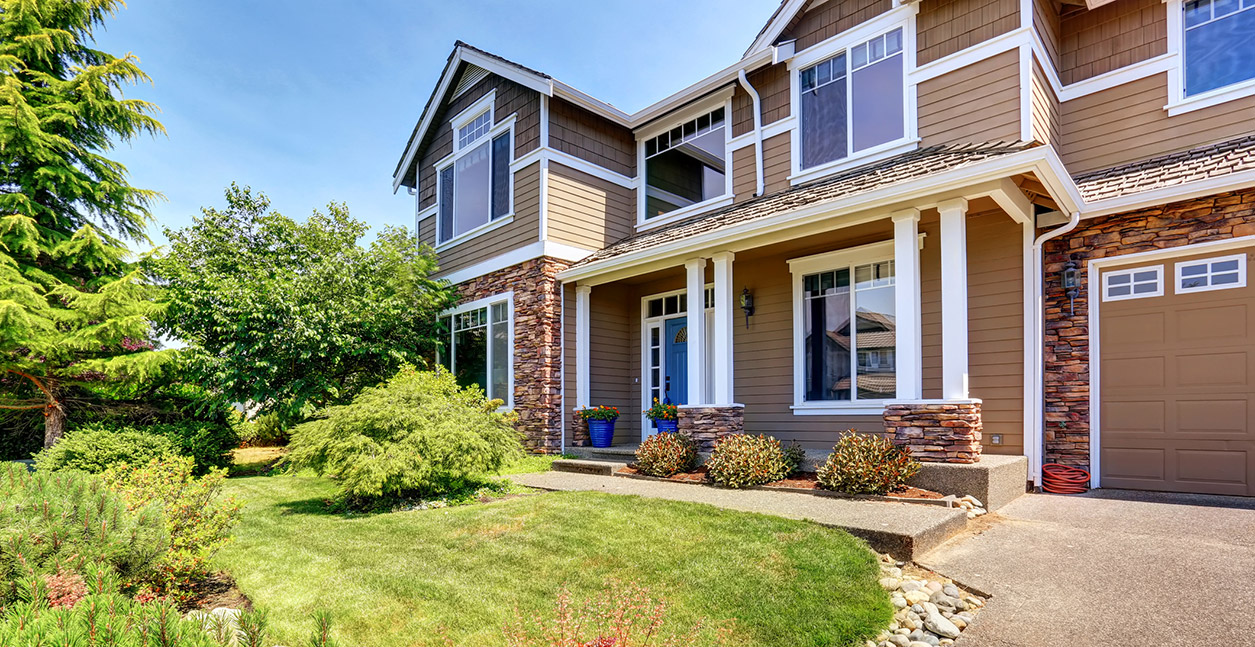 Exterior view of a large home with huge casement and bay windows with a modern steel entry door.