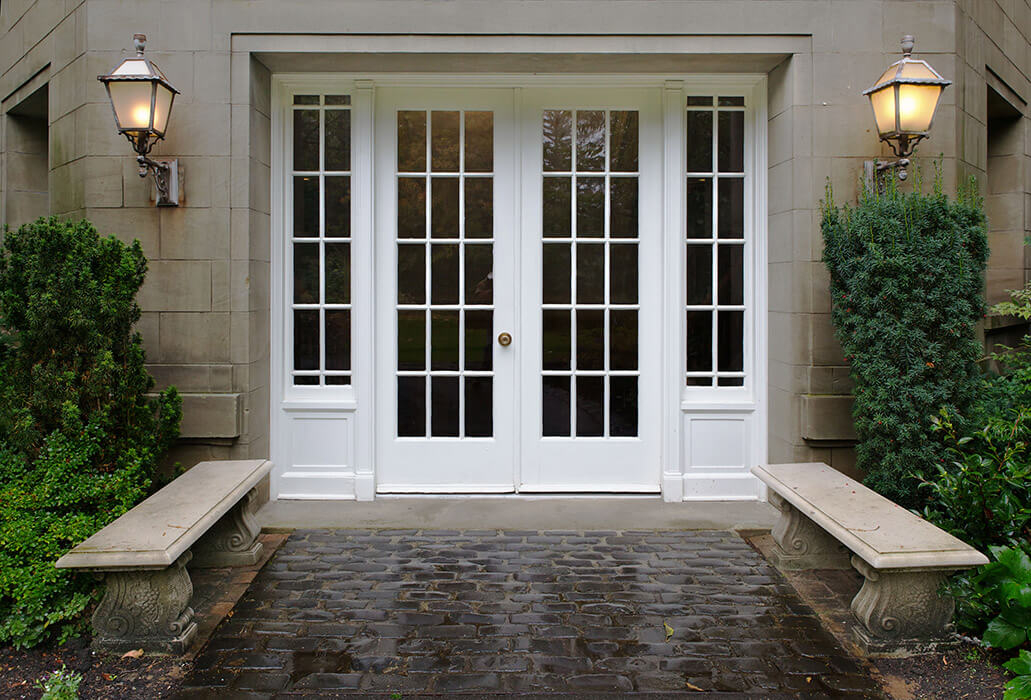 Gorgeous white patio doors swinging out onto a cobblestone path.