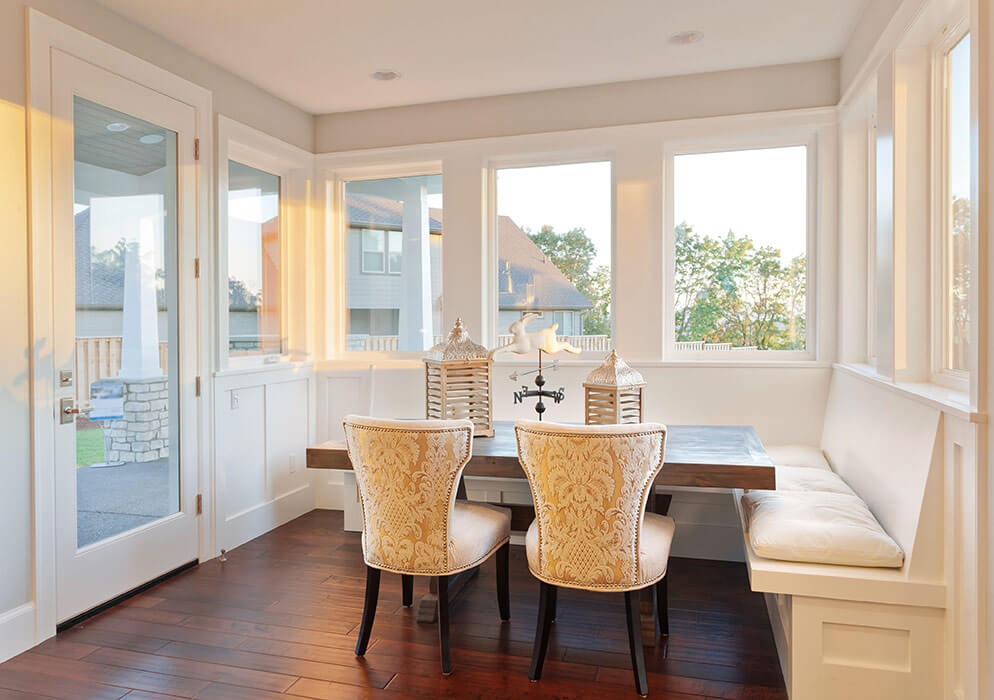 A sleek dining room with many replacement picture windows around it.