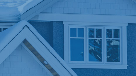 Zoomed-in exterior of large brick house with large windows. Blue overlay.