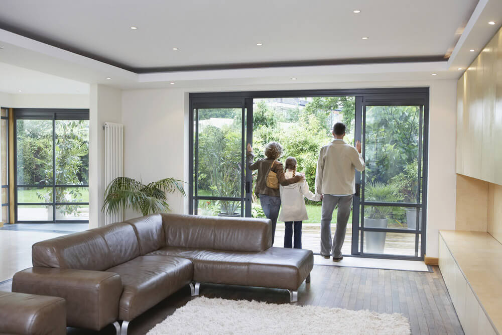 A family looking out of their modern, black patio doors onto their backyard.