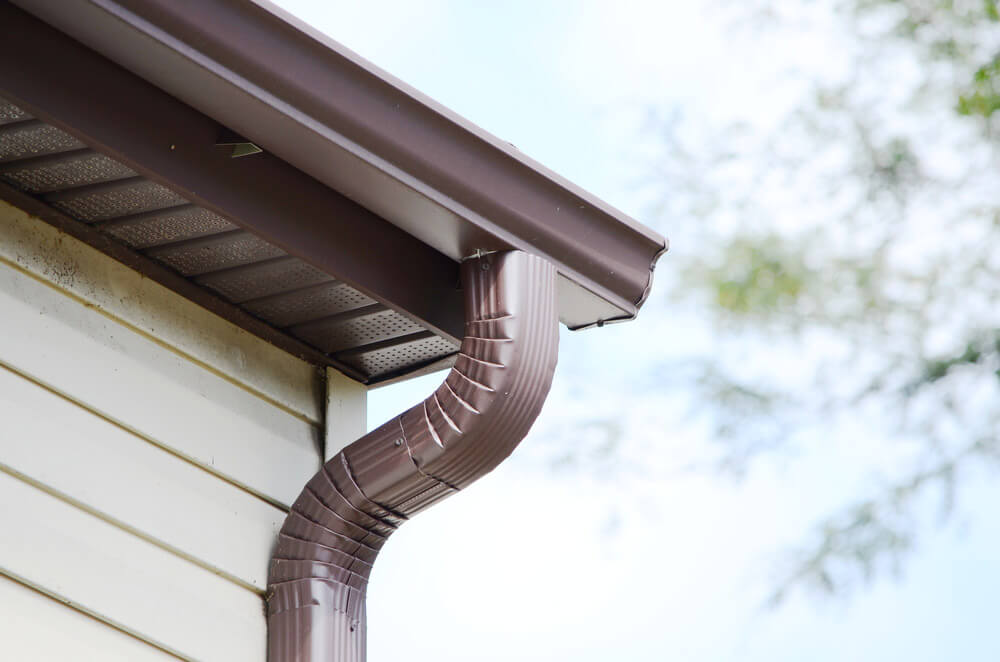 A close-up view of a brown soffit attached to an eavestrough.